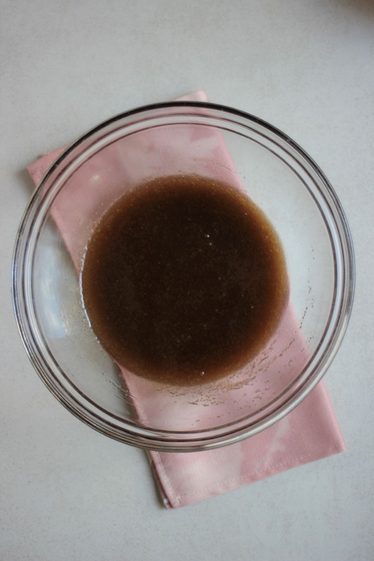 Glass bowl with a brown mixture. A pink napkin under the bowl.