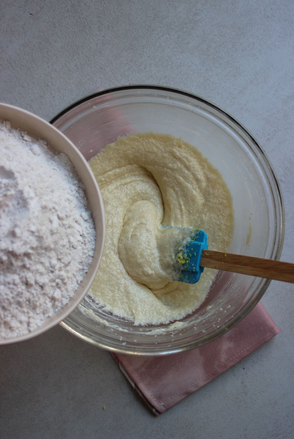Plate with flour about to be poured in a glass bowl with a mixture.