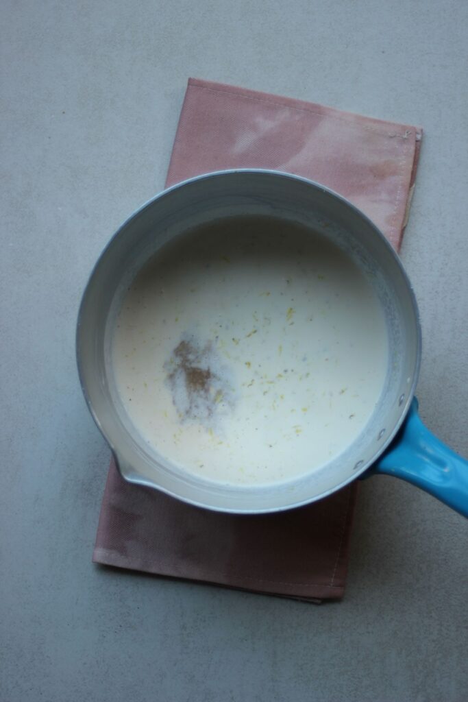 A saucepan with a white liquid and lemon zest.