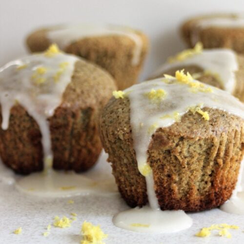 Matcha muffins with lemon icing falling down, on a white surface.