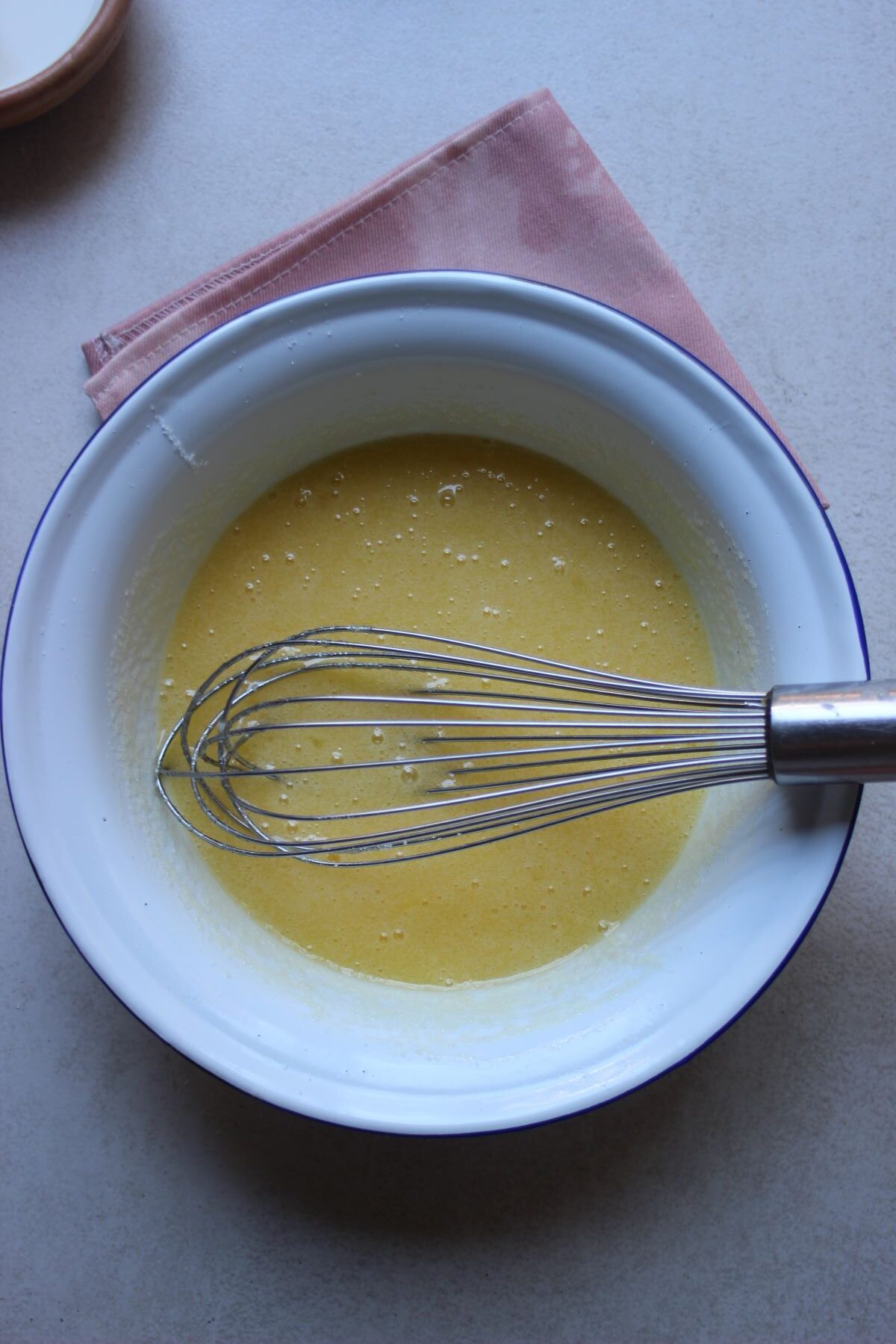 Vanilla loaf cake process: a bowl with beaten eggs and a hand whisk.