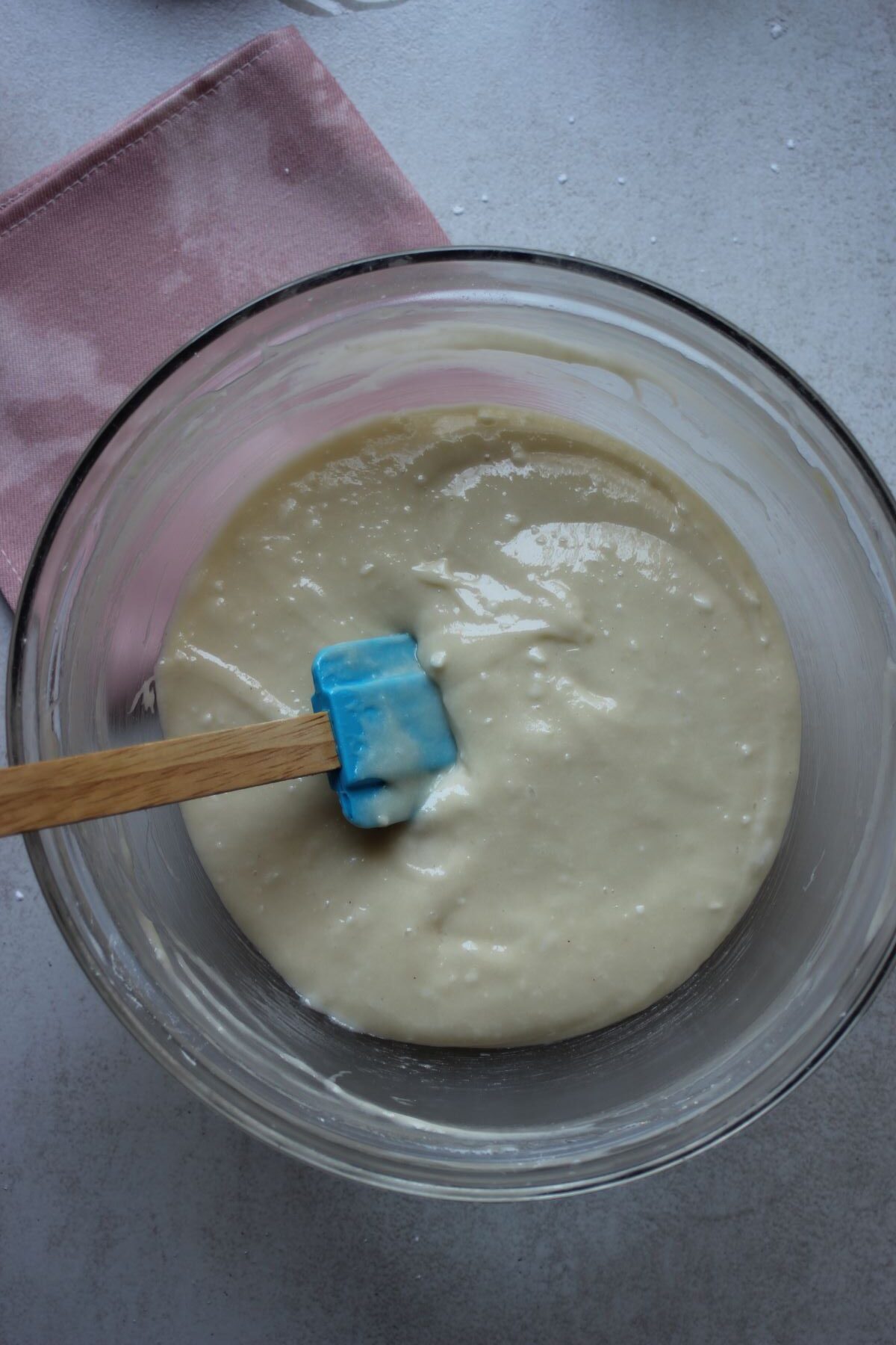 Glass bowl with the vanilla loaf cake mixture and a rubber spatula.