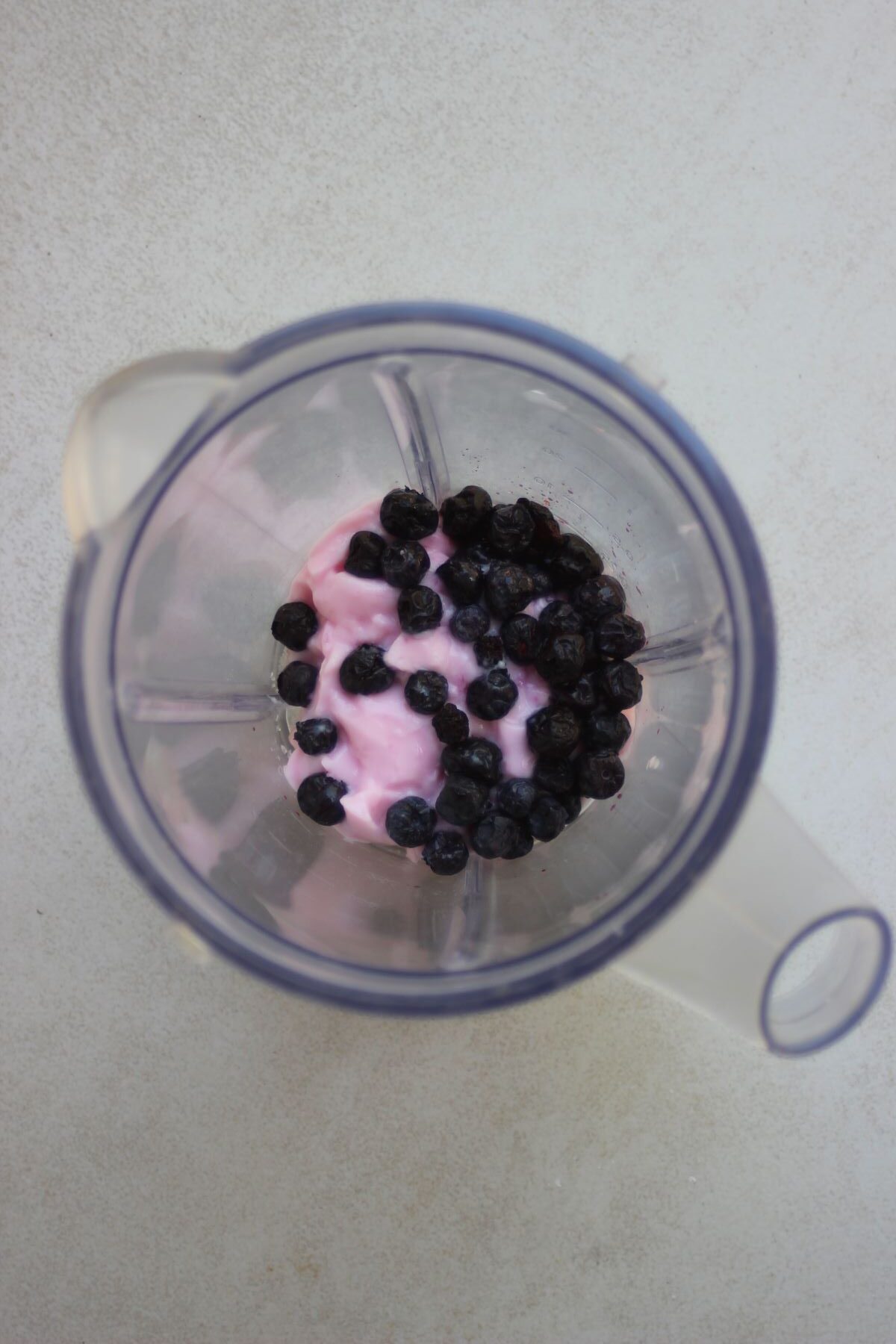 A blender with strawberry yogurt and blueberries.