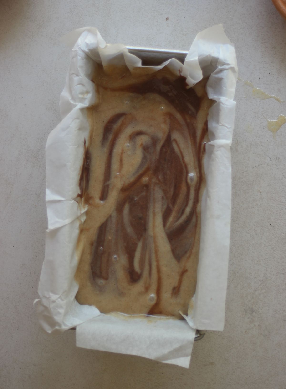 Loaf cake pan with parchment paper and the mixture.