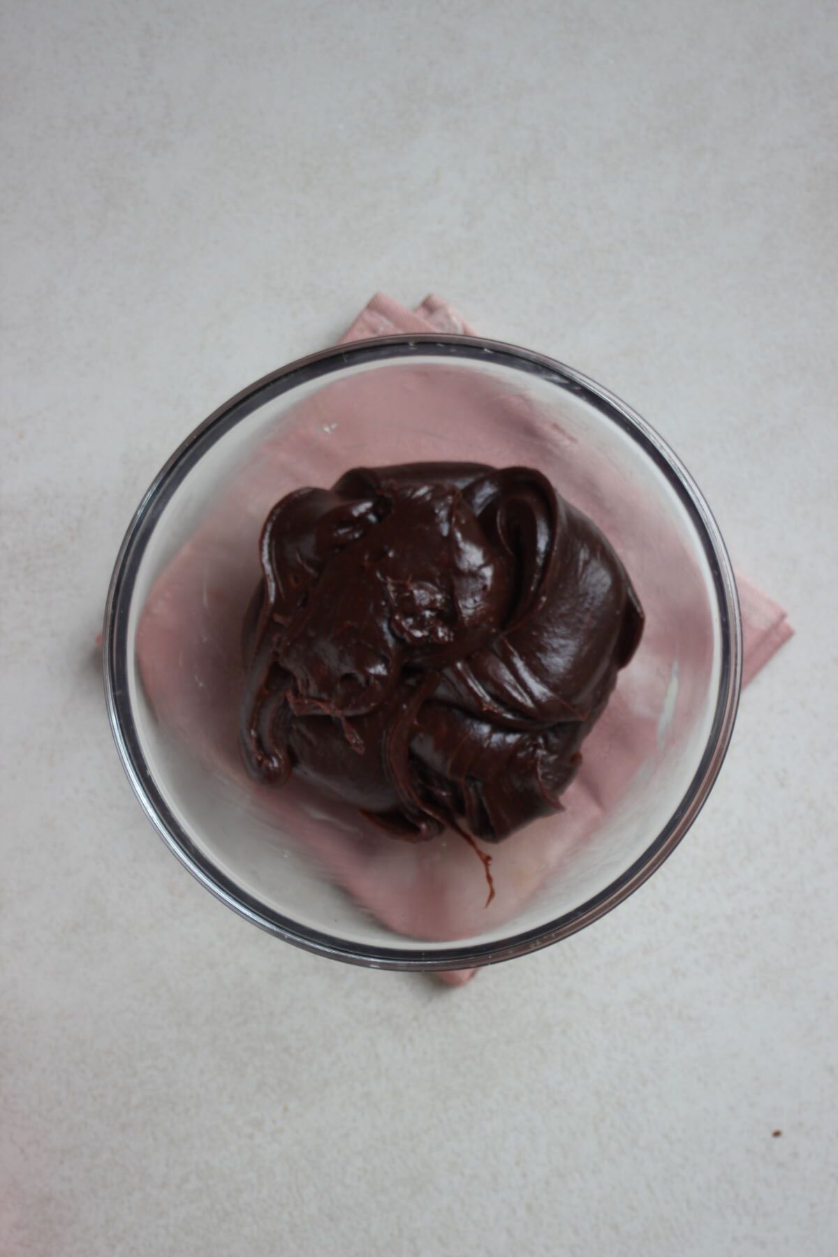 Glass bowl with a big chocolate ball. Pink napkin under the bowl.