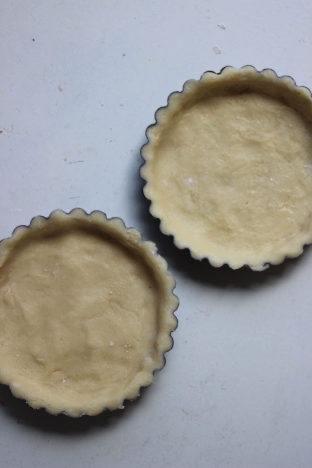 Two raw tart dough in their mold.