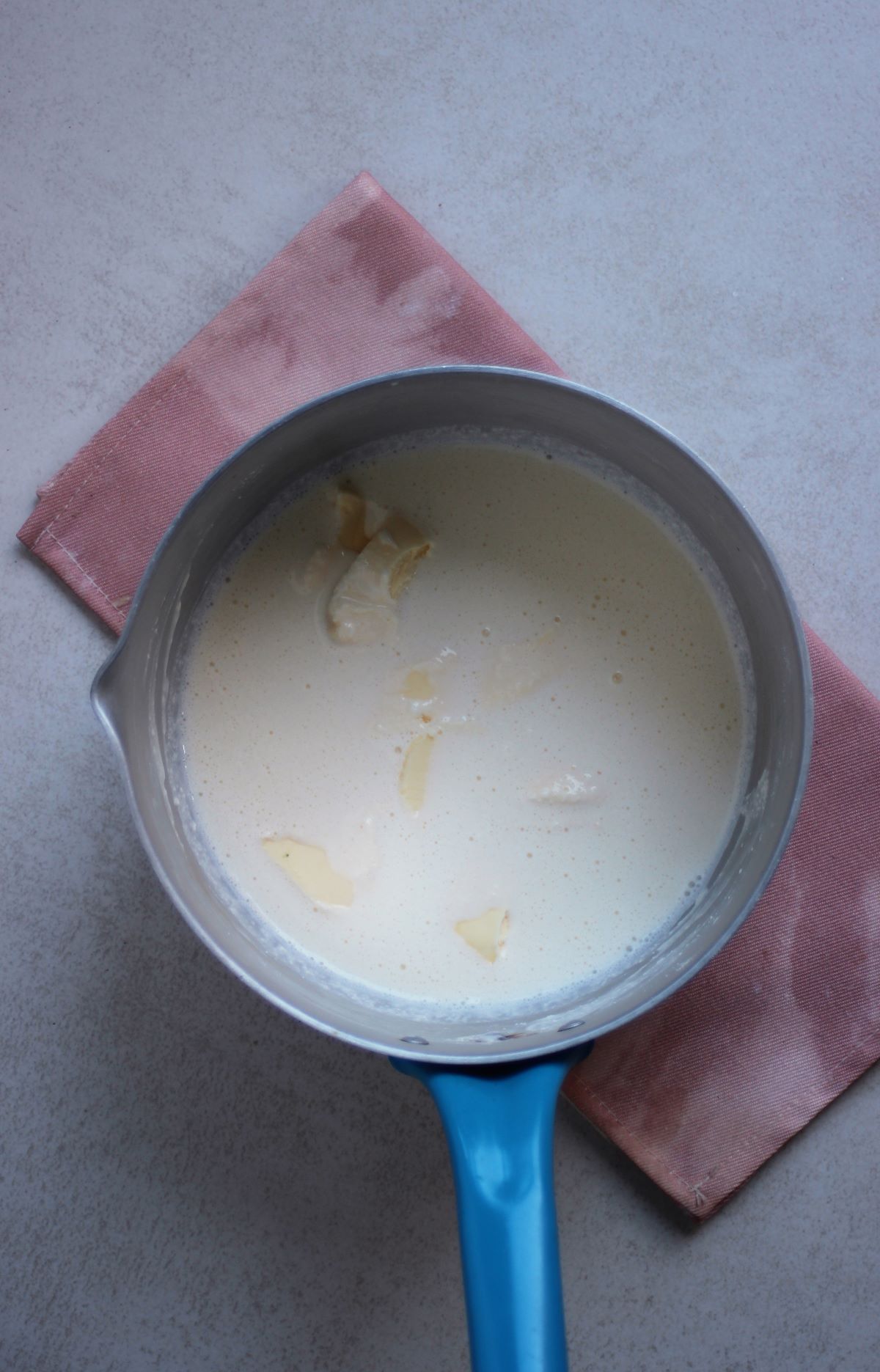 A deep proof pan with milk and cream cheese seen from above.