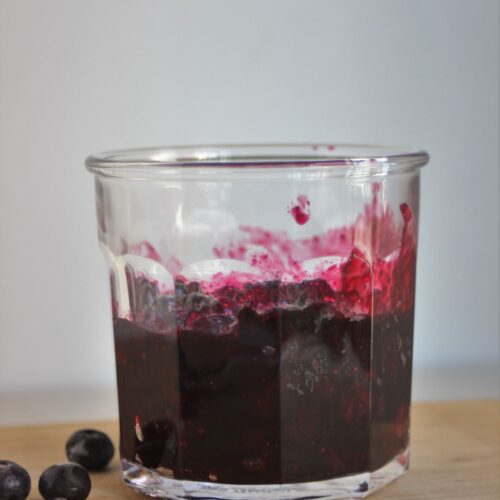 A Jar with blueberry sauce. Fresh blueberries on the side.