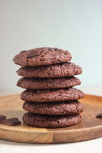 A tower of chocolate cookies on a wooden plate.