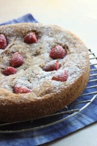Almond and strawberry cake on a round rack.
