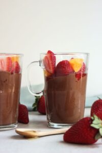 Glass cup with chocolate mousse, strawberries, and peaches.