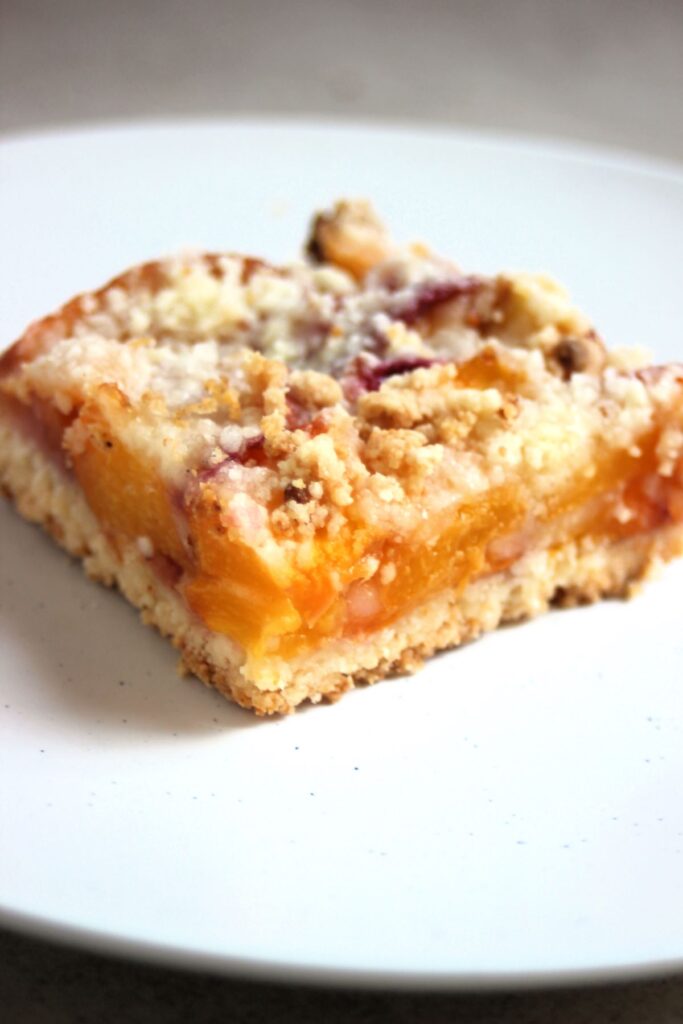 Peach crumb bar on a white plate.