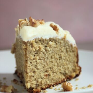 Front view of a sweet potato slice with cream cheese frosting on a white plate.