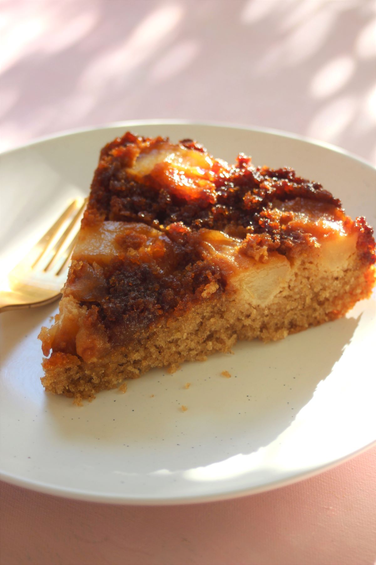 Pear upside-down cake portion on a white plate and a golden fork.