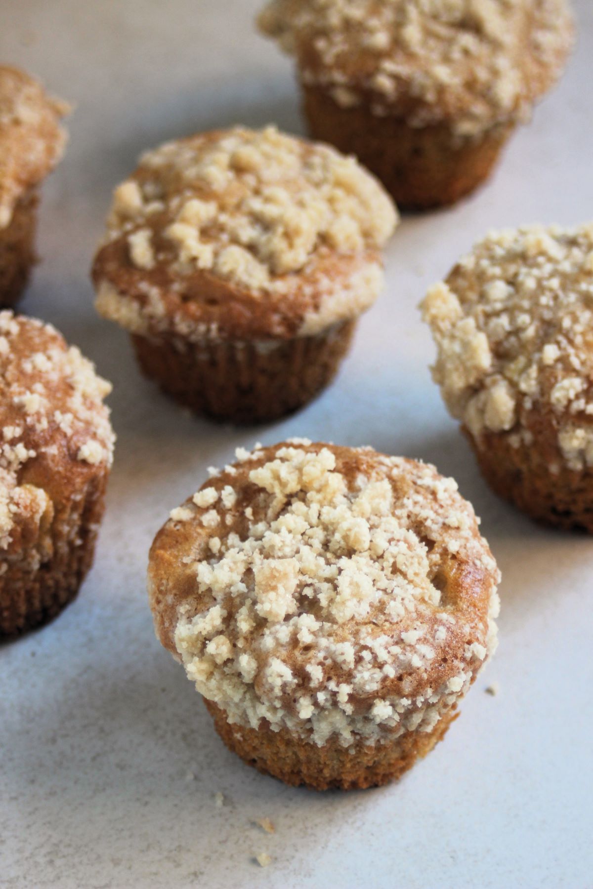 Apple crumb muffins on a white surface.