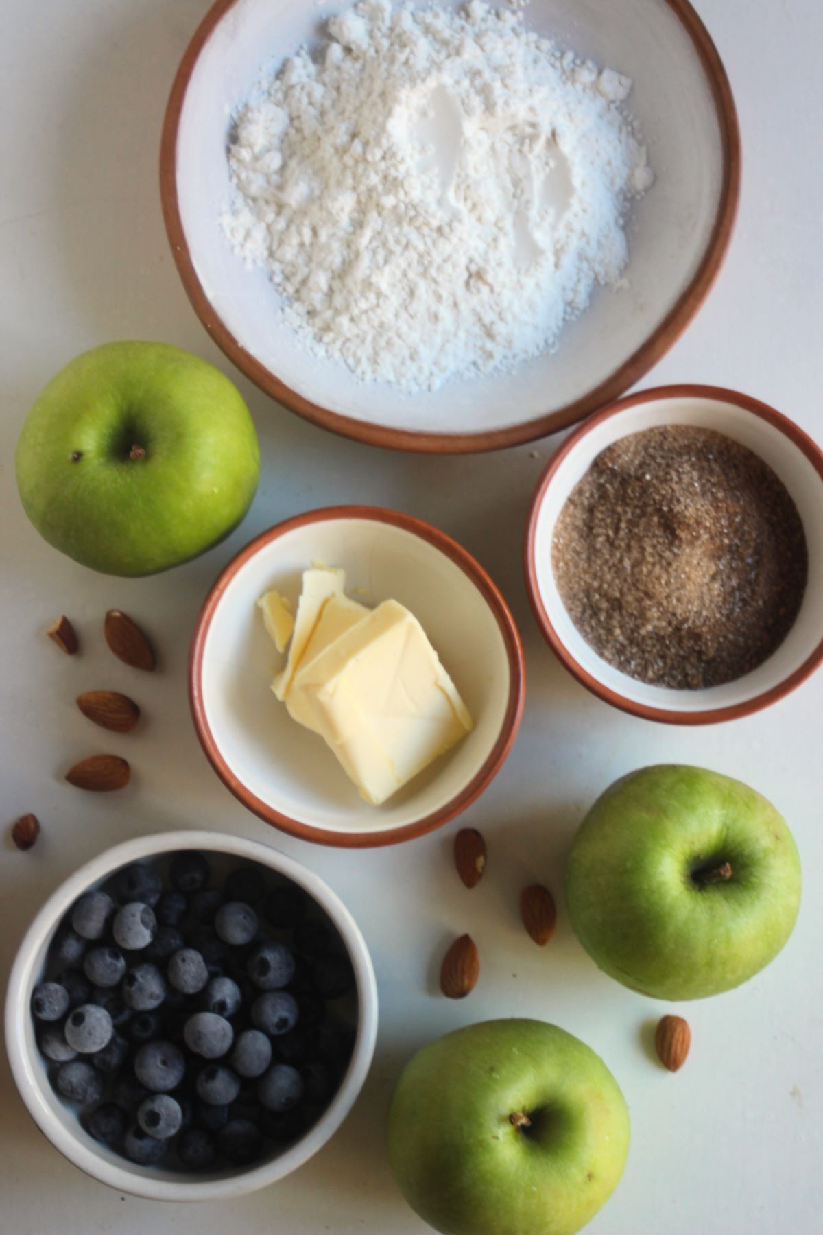 Apple crumble ingredients on a white surface seen from above.