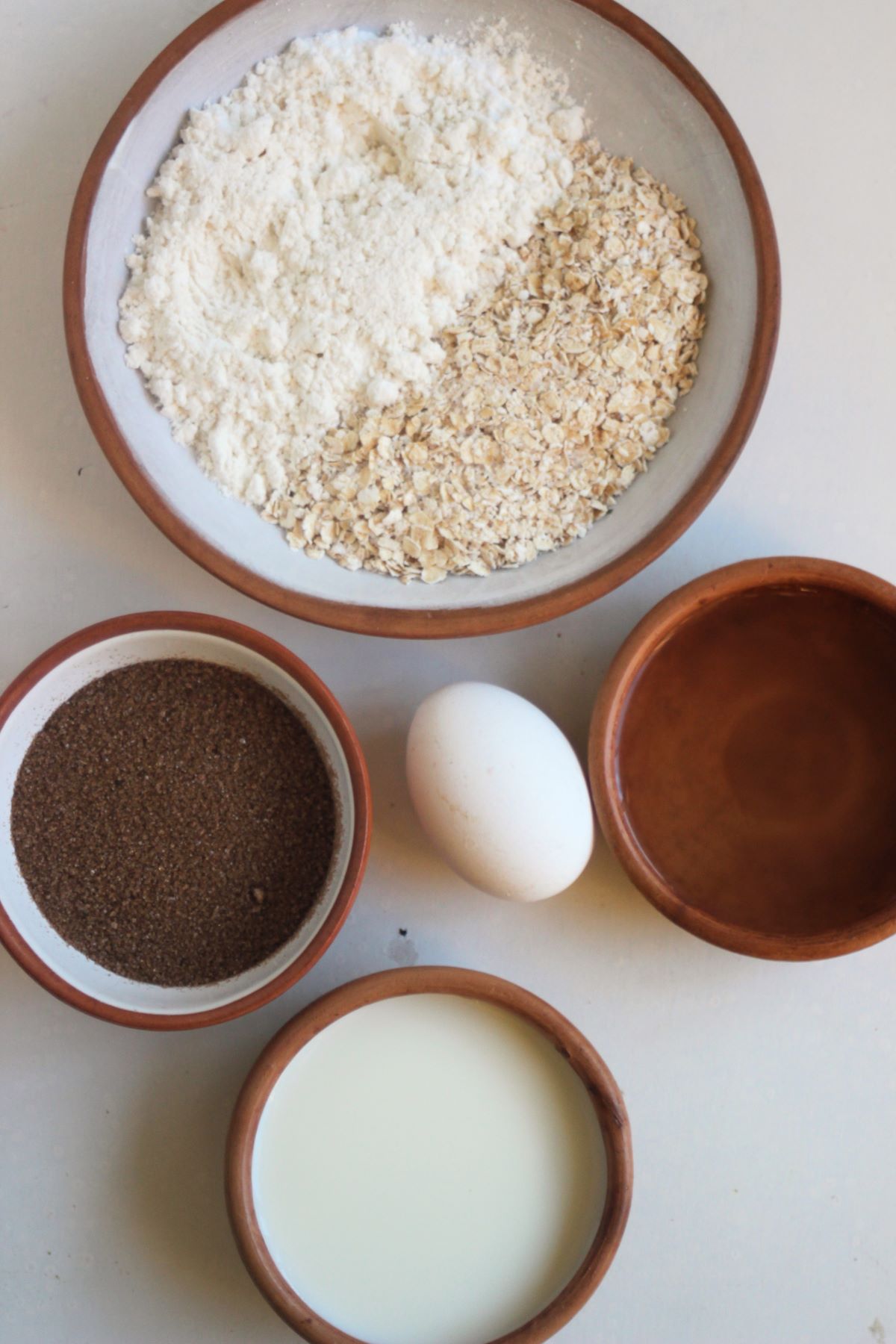 Oatmeal muffins ingredients on a white surface seen from above.