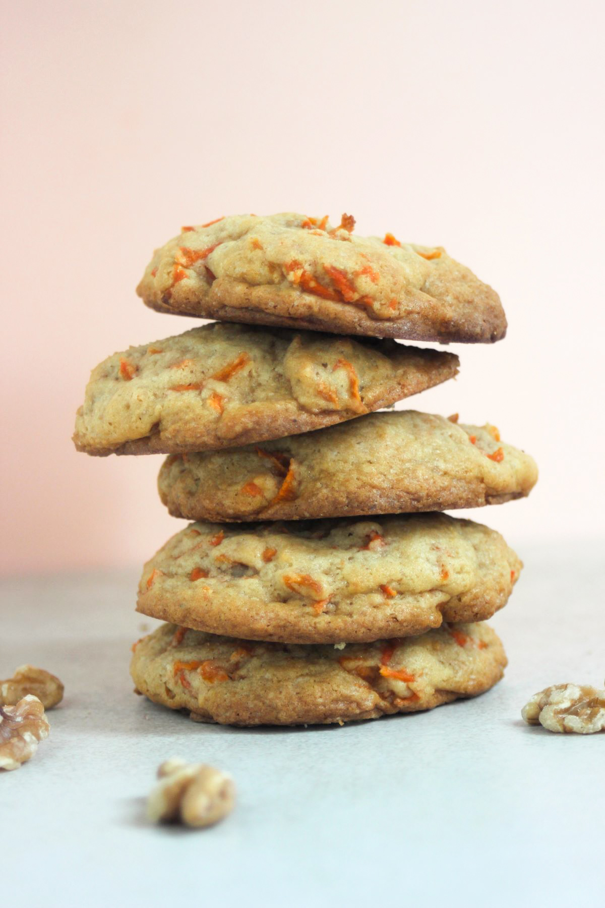 A tower of carrot cake cookies on a white surface, Pink background.