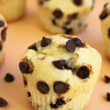 Chocolate chip muffins on a light orange surface,