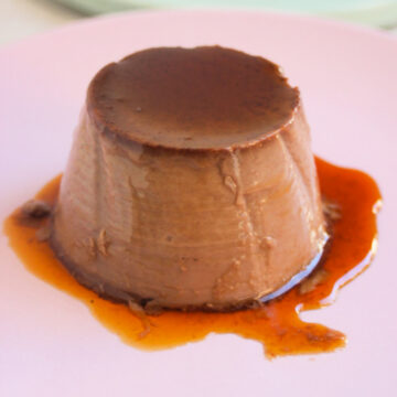 Chocolate flan with caramel on a pink plate.