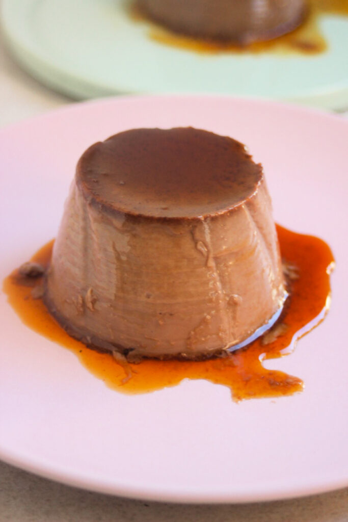 Chocolate flan with caramel on a pink plate.