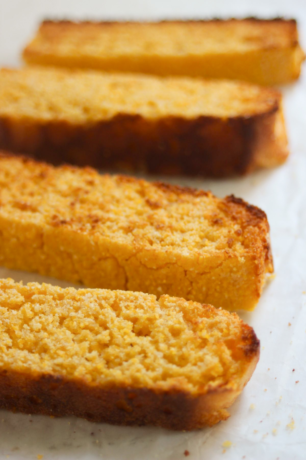 Slices of corn bread on a white surface.