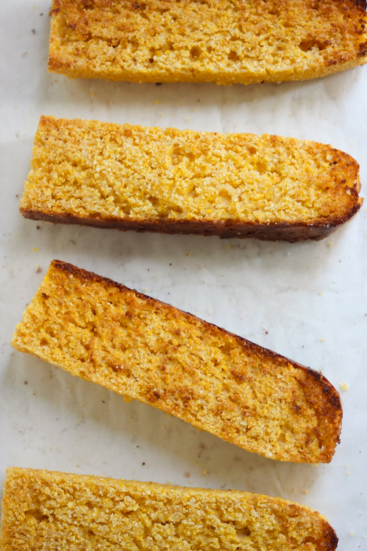 Slices of corn bread on a white surface seen from above.