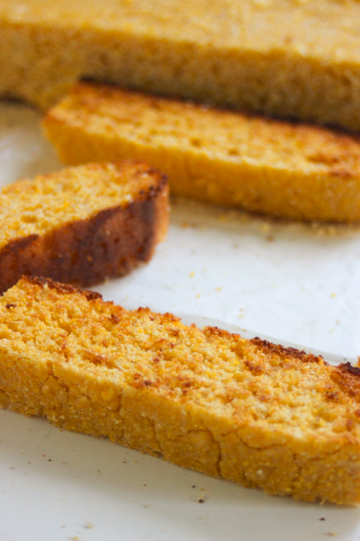 Slices of corn bread on a white surface.