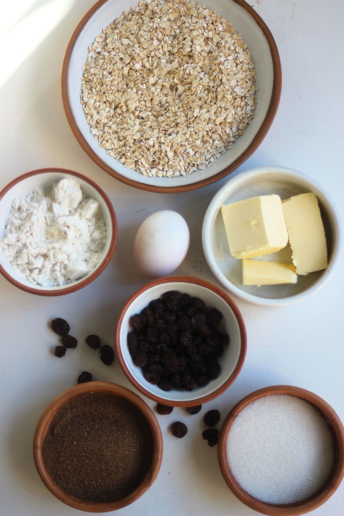 Oatmeal raisin cookies ingredients on a white surface seen from above.