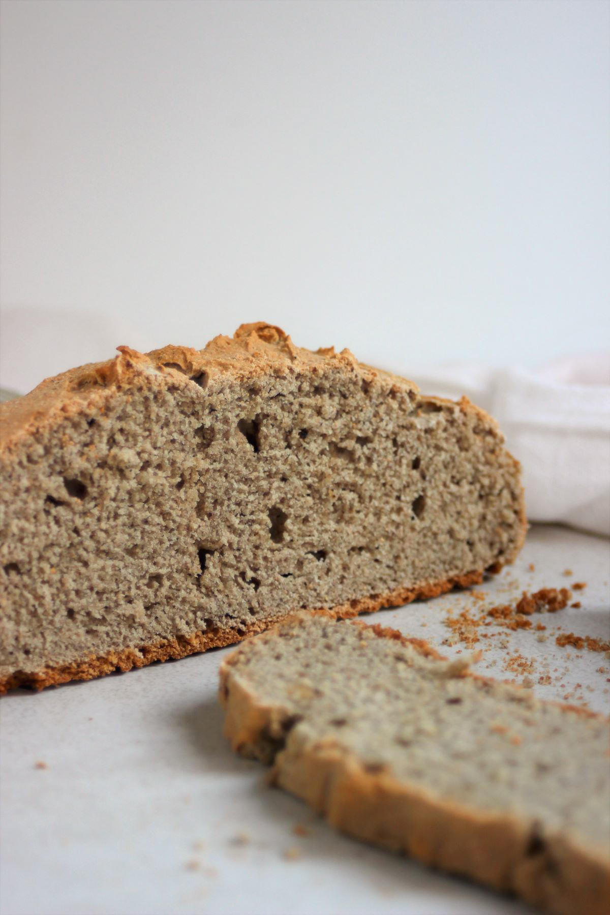 A piece of soda bread and one slice of bread on a white surface.