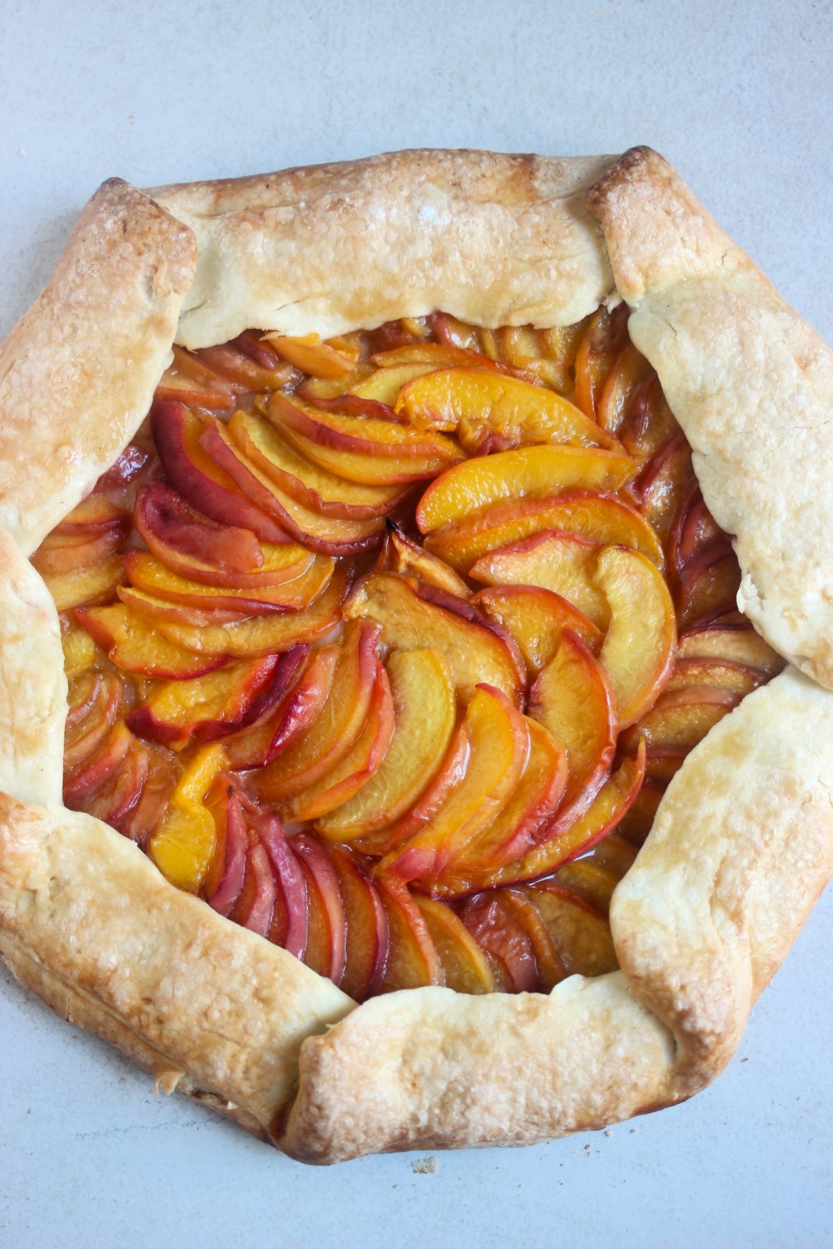 Peach galette on a white surface seen from above.