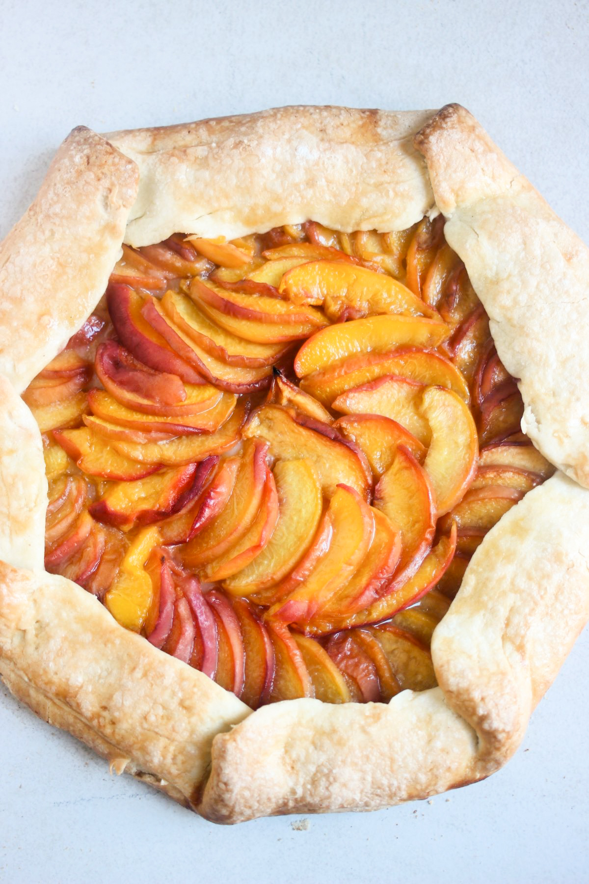 Peach galette on a white surface seen from above.