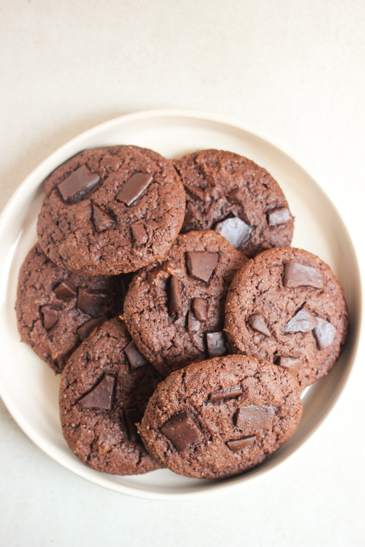 Many chocolate cookies on a white plate.