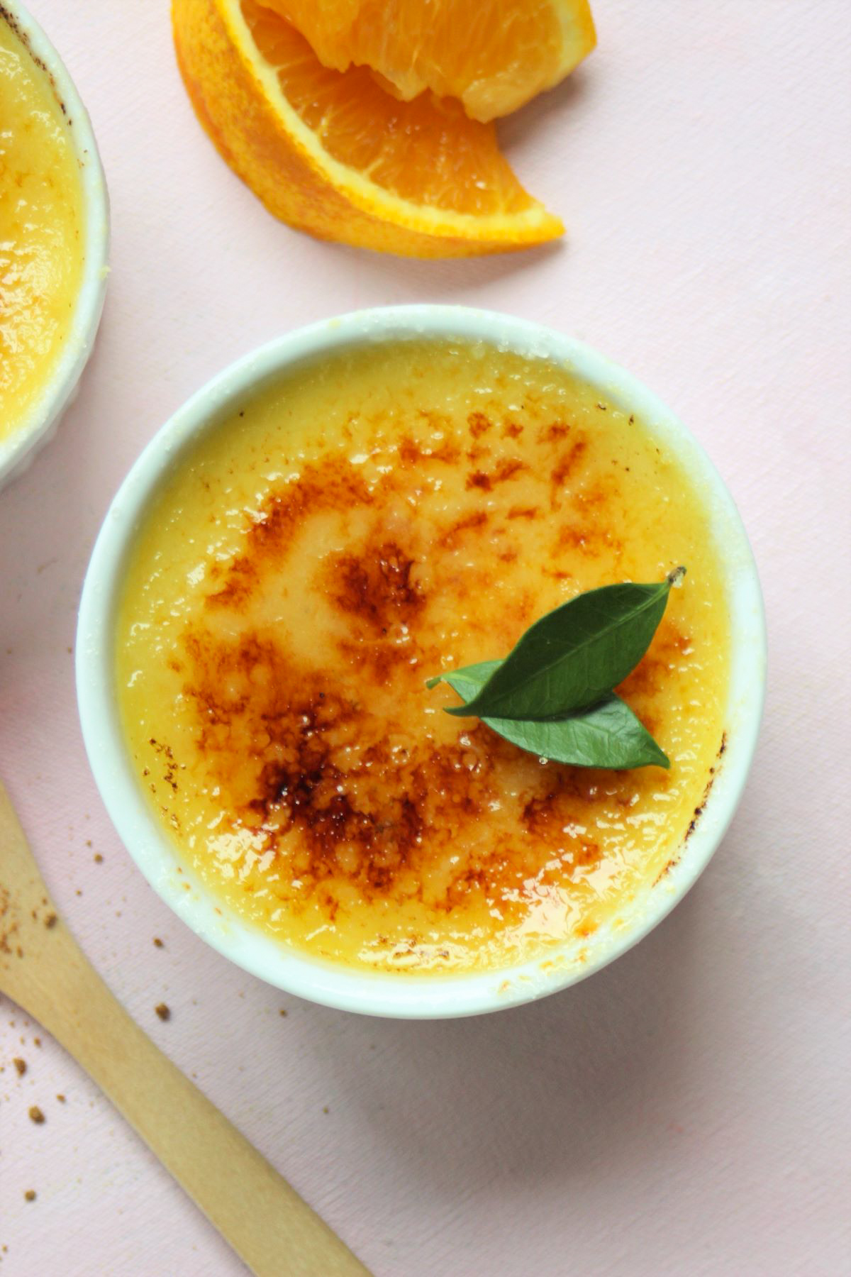 White ramekin with creme brulee. Orange slices on the side.