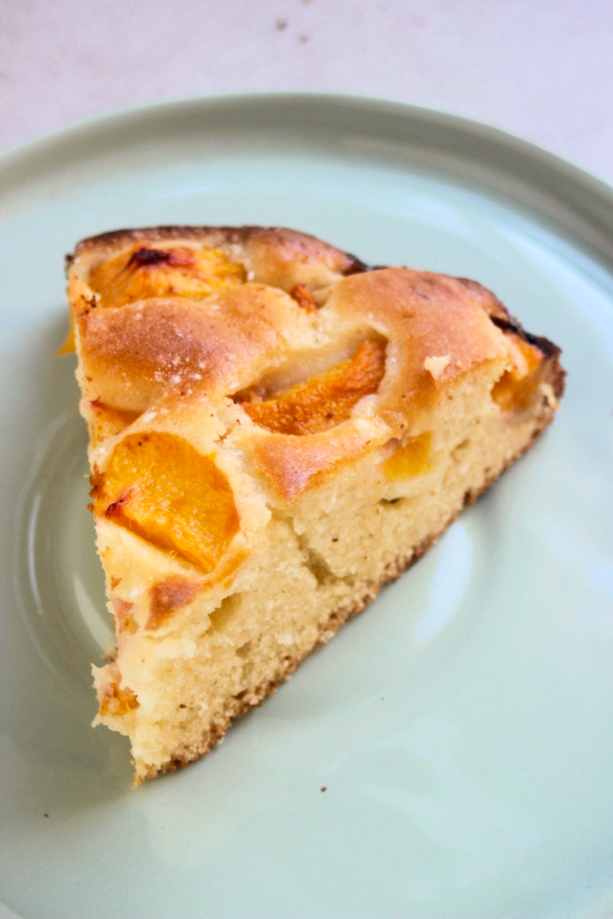 A portion of peach cake on an aqua green plate.