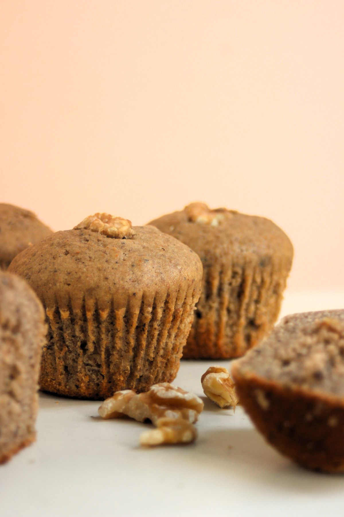 Banana muffins on a white surface and walnuts on the side.