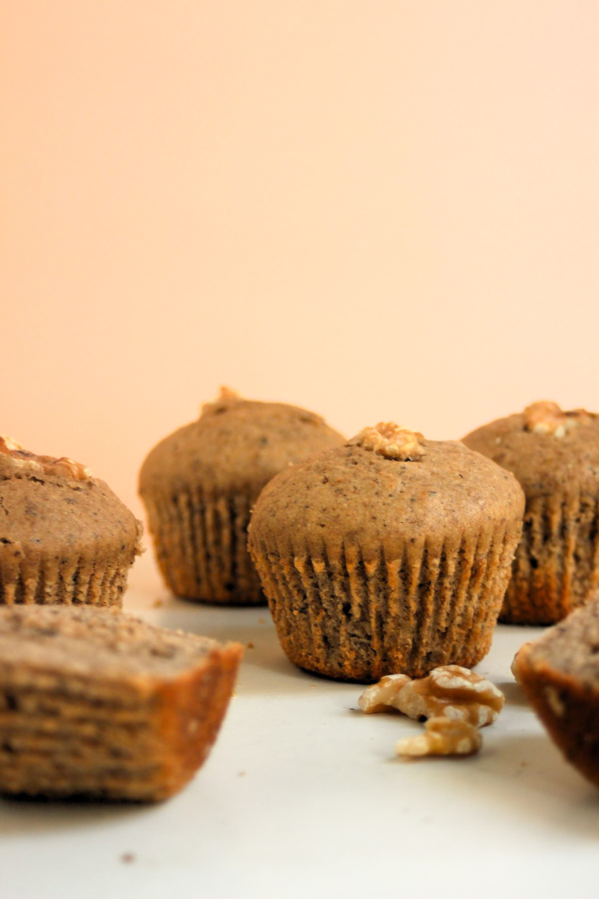 Banana muffins on a white surface and walnuts on the side.