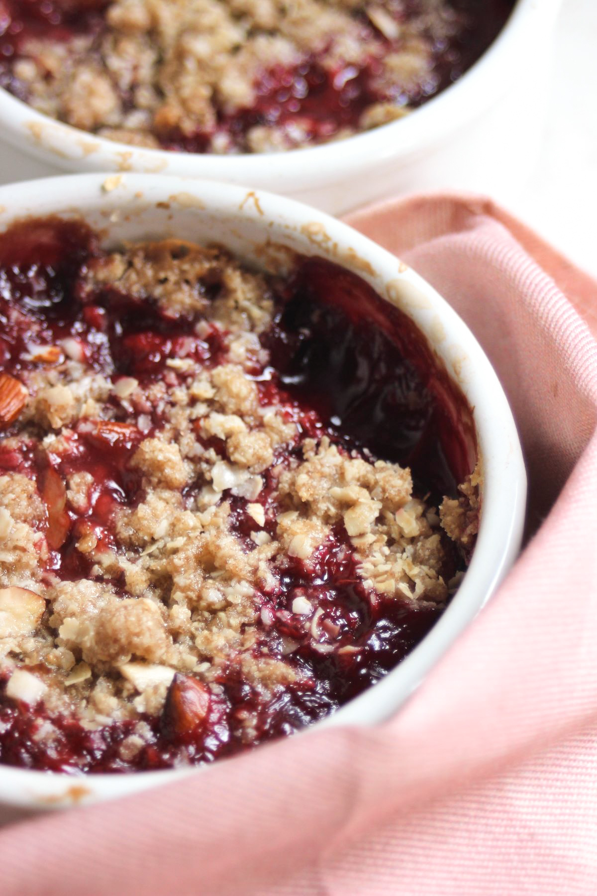 Plum crisp on a ramekin and a pink napkin around it.