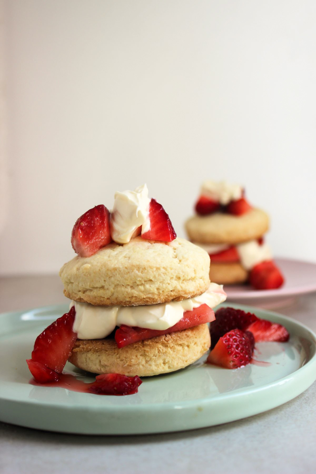 Strawberry shortcake on and strawberries on the sides. Another shortcake behind.