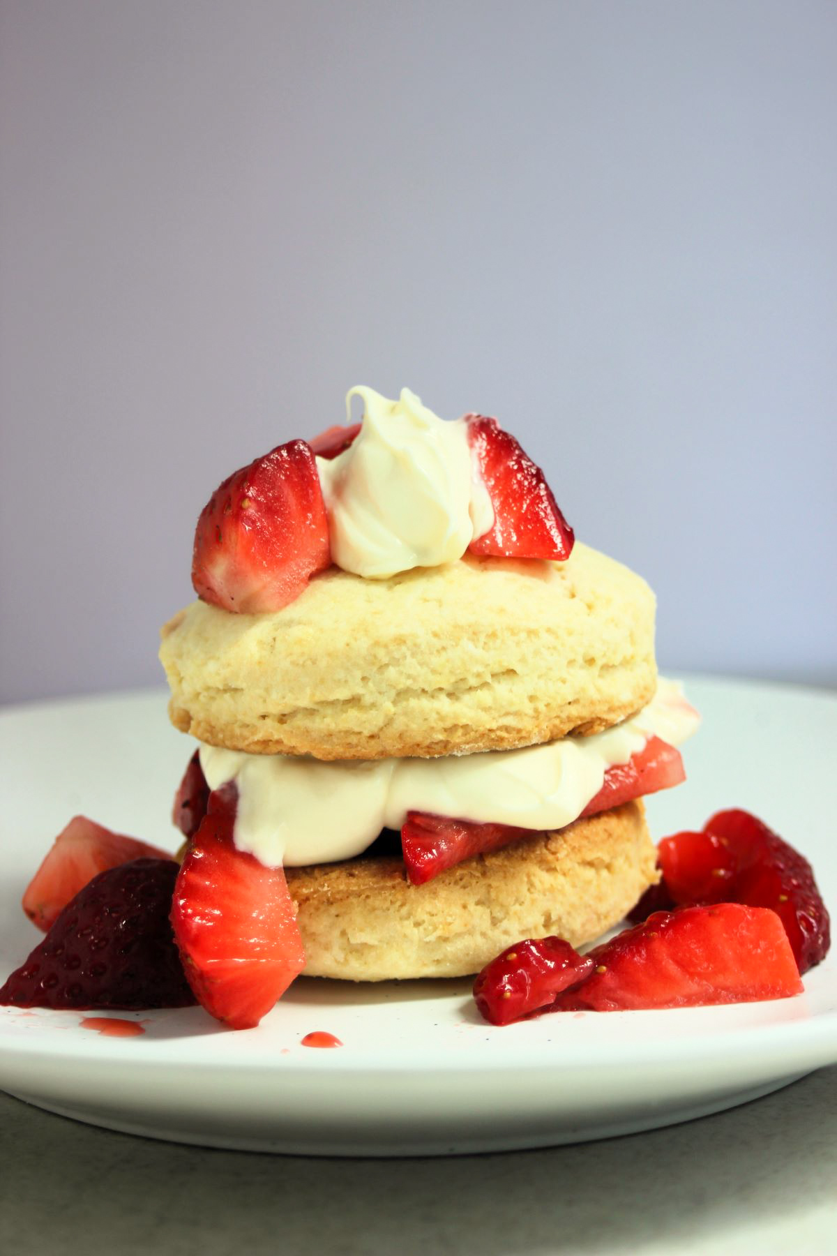 Strawberry shortcake on a white plate and strawberries on the sides.