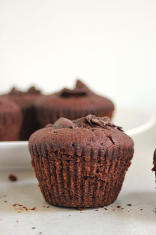 Chocolate muffin on a white surface. More muffins on the background.