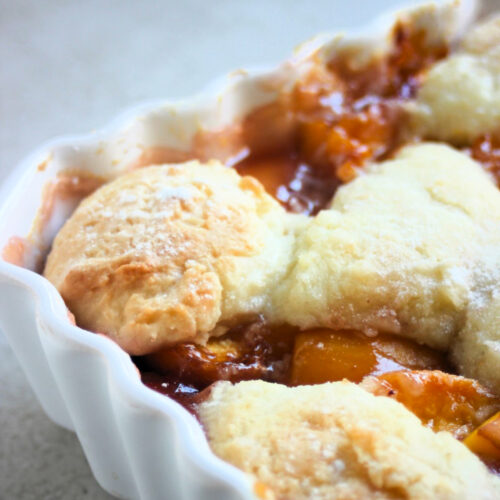 A part of a baking sheet with a peach cobbler seen from close.