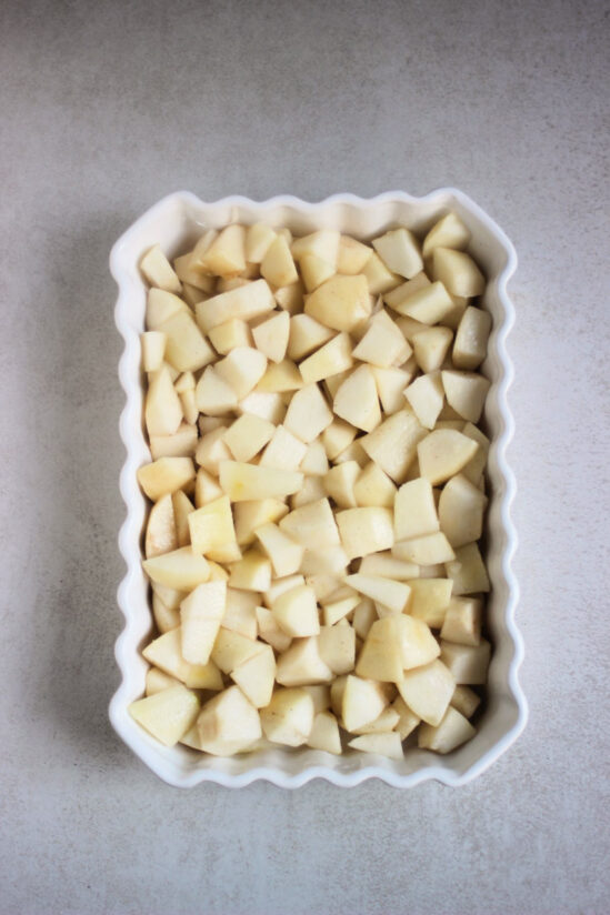 Rectangular white baking dish with chopped pears.