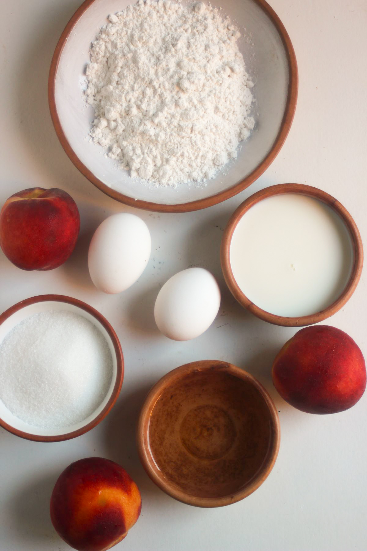 Peach cake ingredients on a white surface seen from above.