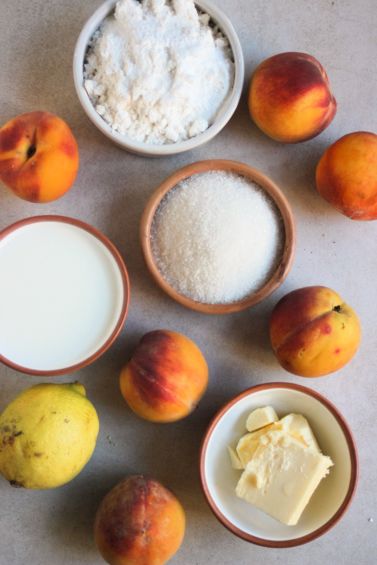 Peach cobbler ingredients on a white surface seen from above.