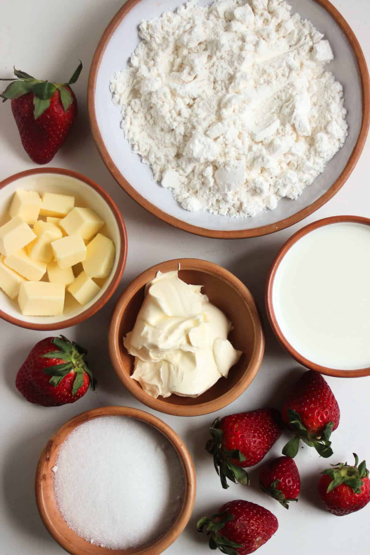 Strawberry shortcake ingredients on a white surface seen from above.