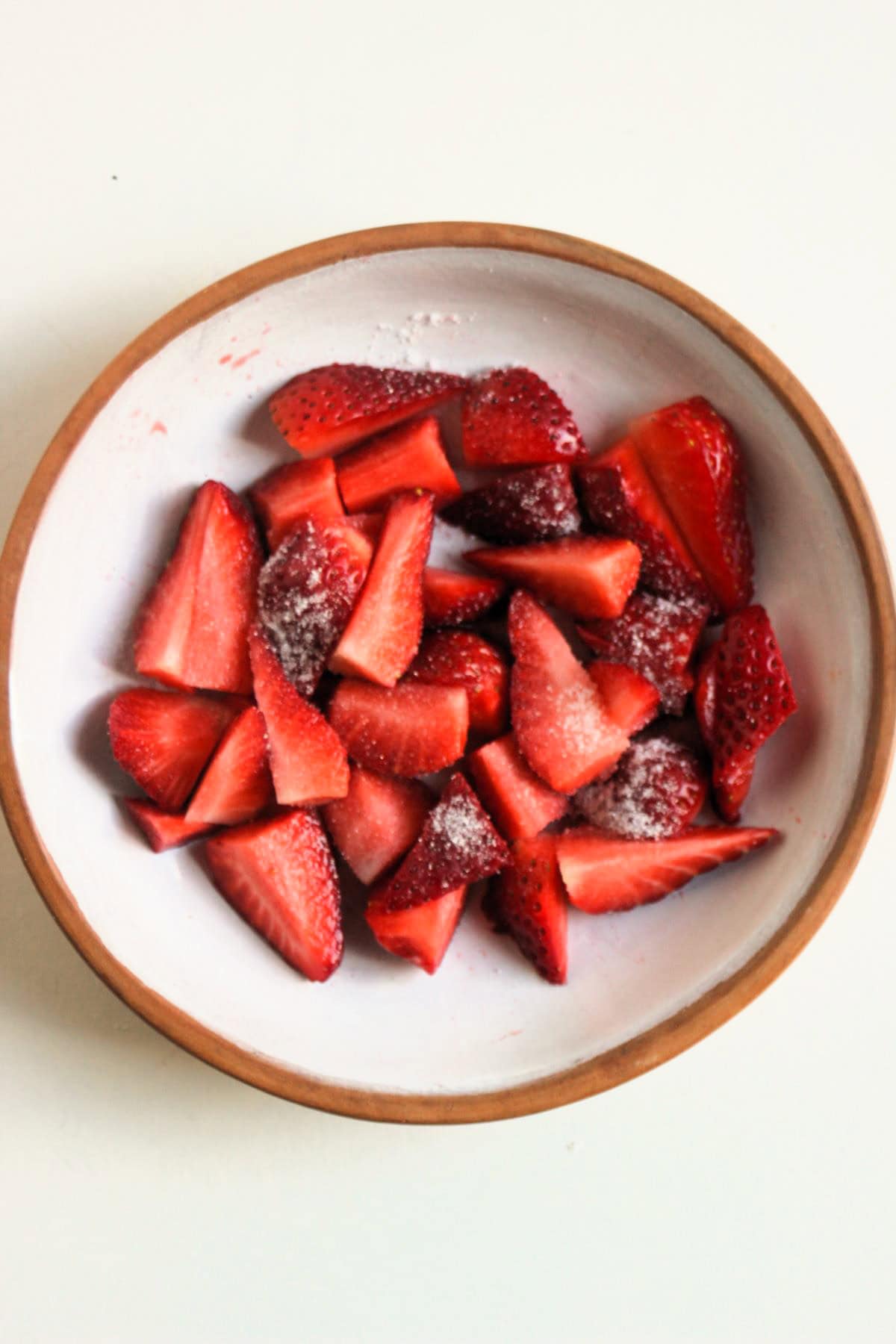 Cut strawberries with sugar on a plate.