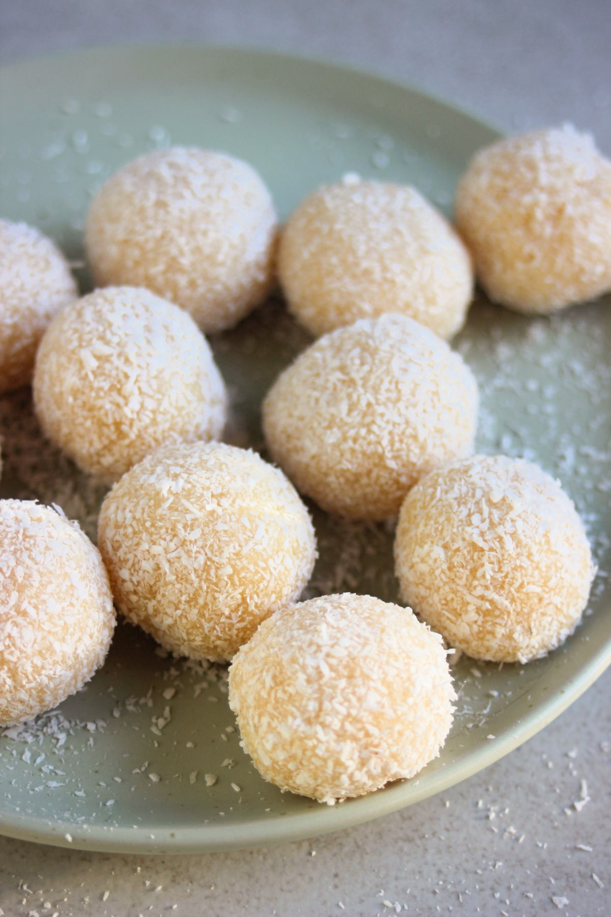 Coconut brigadeiros on an aqua-green plate.