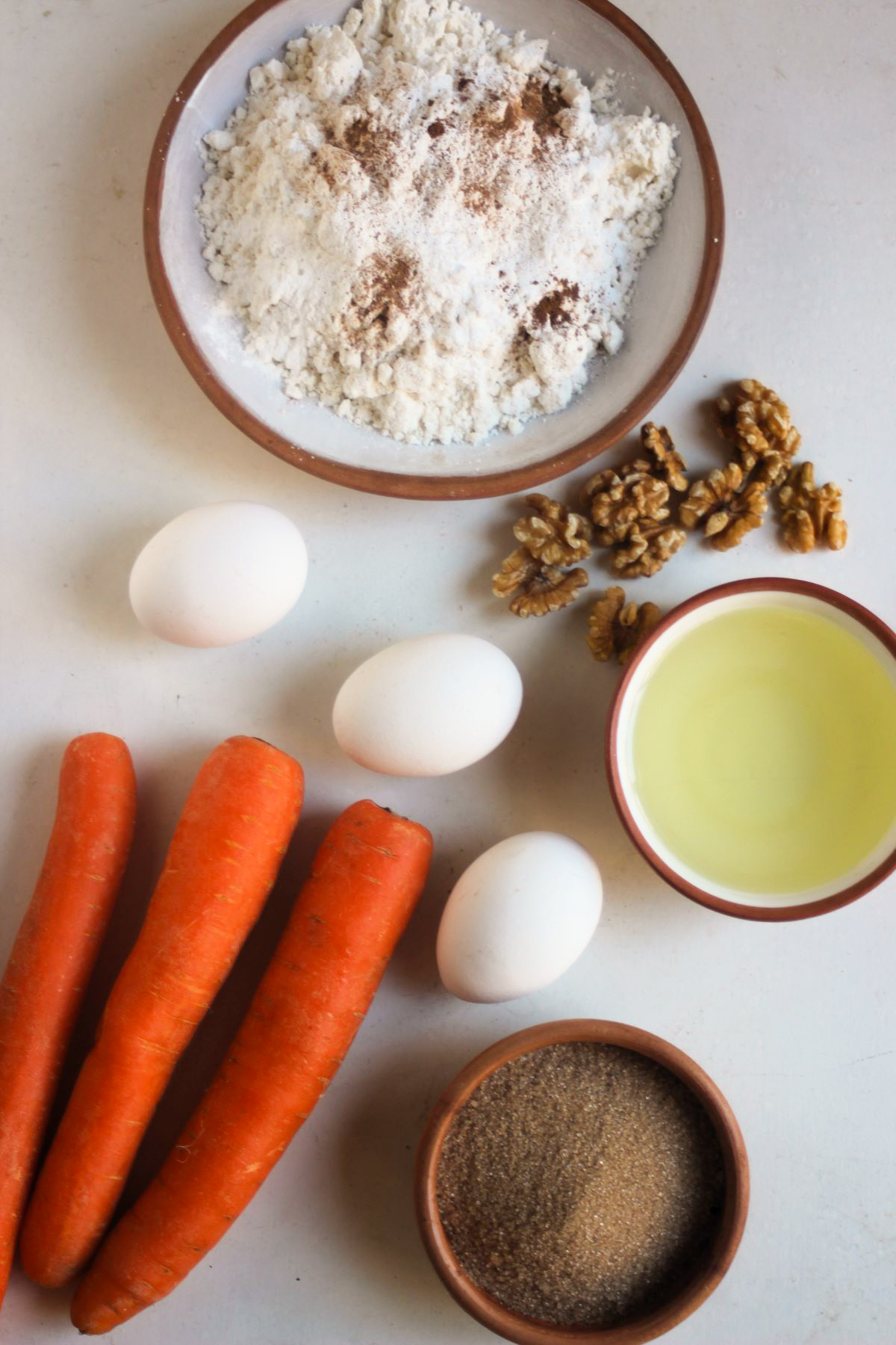 Carrot cake ingredients on a white surface seen from above.