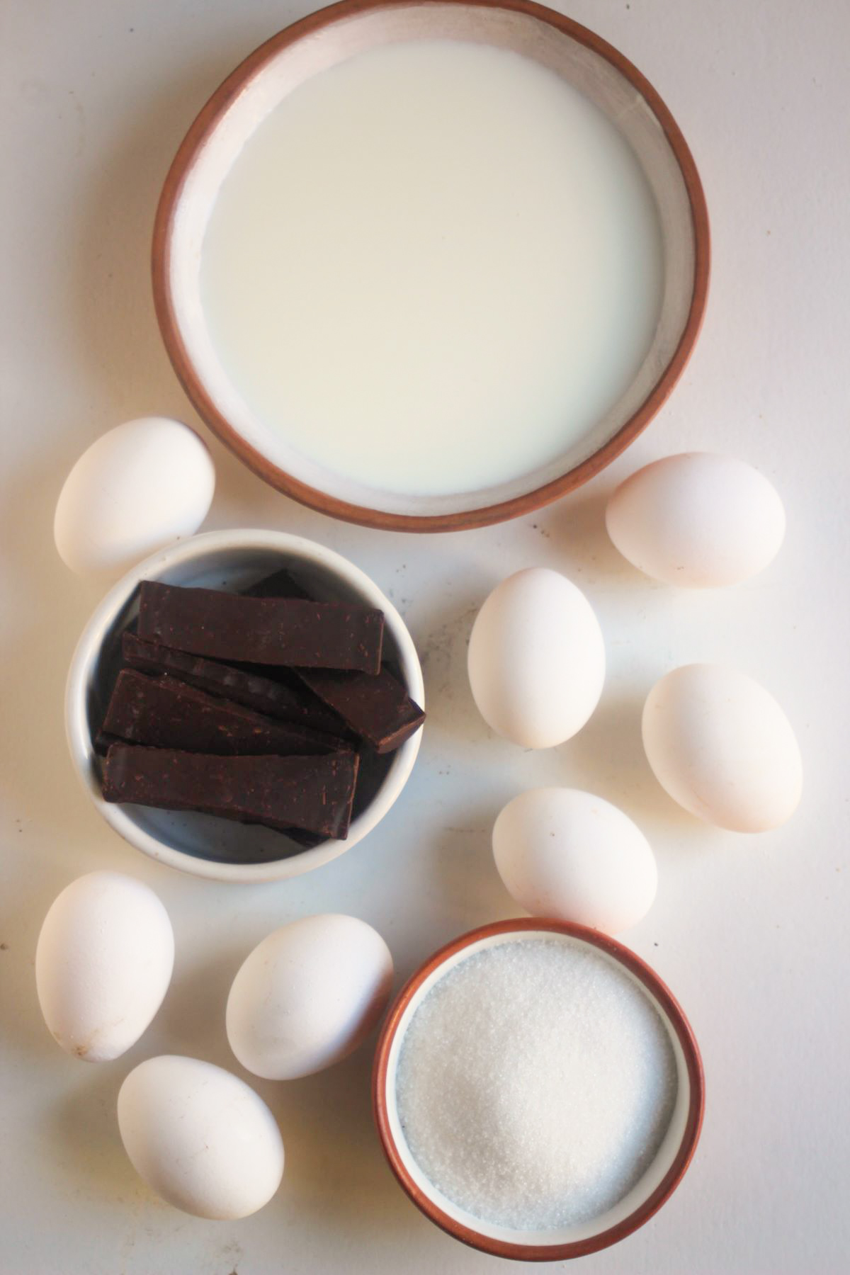 Chocolate flan ingredients on a white surface seen from above.